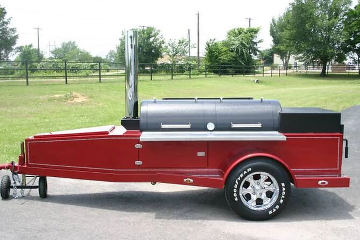 Red Jambo trailer pit with black chamber and chrome stack on a grass lot