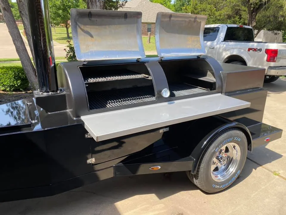 Glossy black Jambo trailer pit with both chamber doors open and stainless shelf down